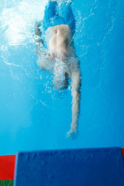 Φωτογραφία στην κορυφή νεαρού σπορ, κολύμπι στην πλάτη στην πισίνα - Φωτογραφία, εικόνα
