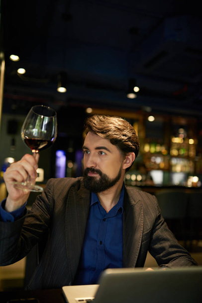 Sommelier betrachtet Rotwein im Glas zur Qualitätsanalyse  - Foto, Bild