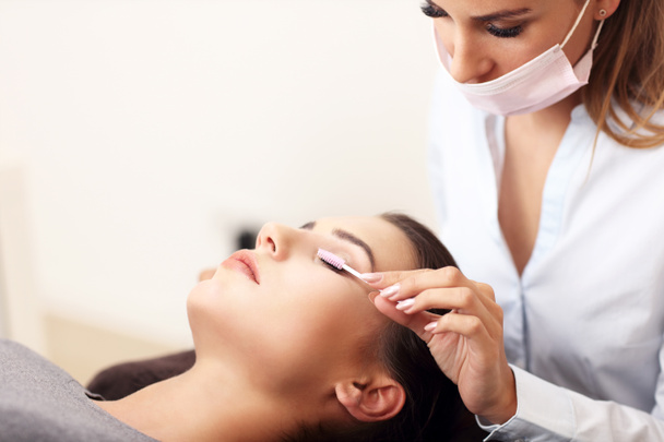 Picture of adult woman having eyelash extension in professional beauty salon - Photo, Image