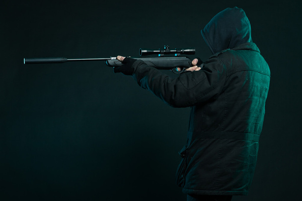 Sniper with beard in black holding gun. Studio shot. - 写真・画像
