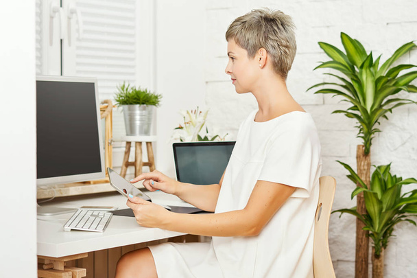 güzel iş kadını bir beyaz elbise oturma bir resepsiyon ve işleri bir tablet üzerinde - Fotoğraf, Görsel