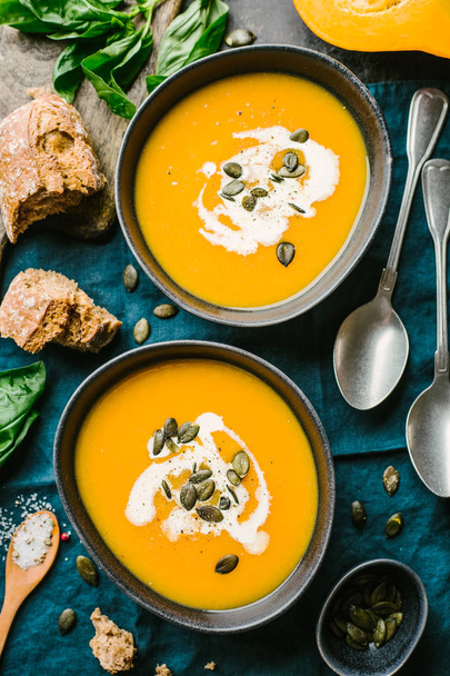 Autumn food - pumpkin soup with cream and seeds in bowls on table. Served for dinner. View from above with copy space. - Photo, image