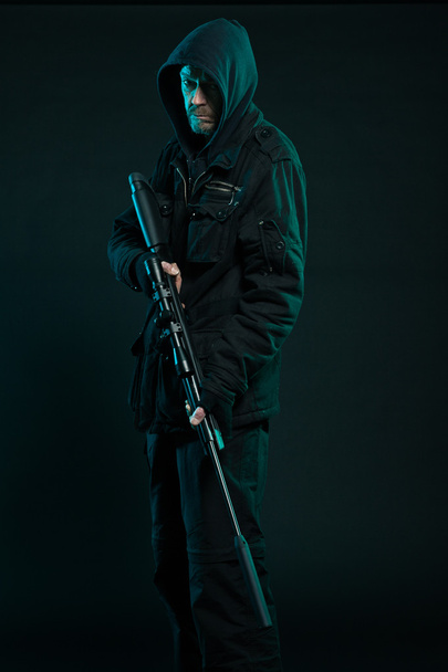 σκοπευτής με γενειάδα σε μαύρο εκμετάλλευση πυροβόλο όπλο. Studio που γυρίστηκε. - Φωτογραφία, εικόνα