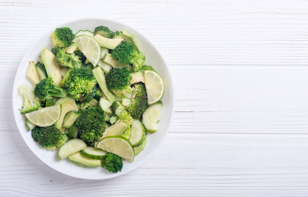 Green salad with avocado , broccoli , cucumber and lime . Healthy vegetarian salad - Fotoğraf, Görsel