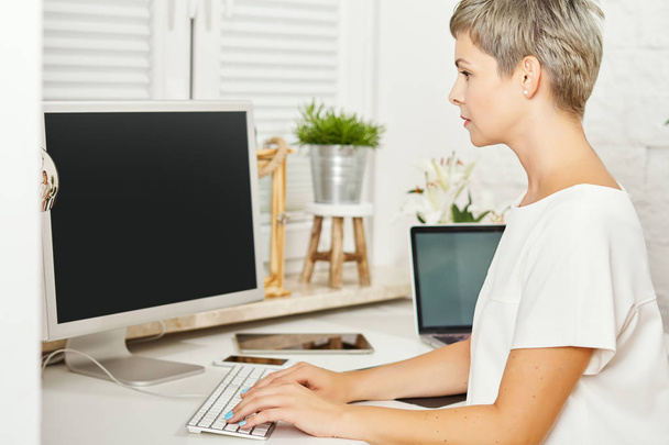 piękna kobieta w białej sukni siedzi przy biurku i działa na komputerze - Zdjęcie, obraz