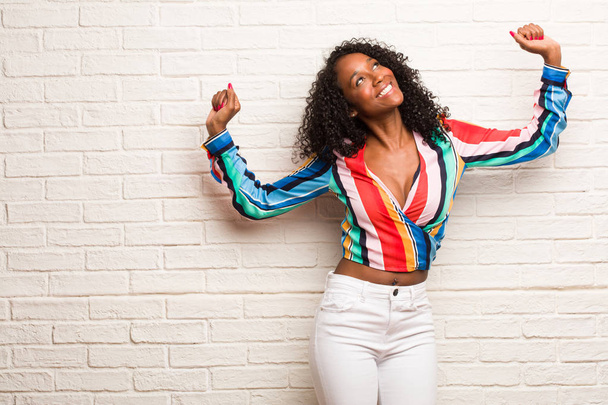 Nuori musta nainen värikäs paita tanssia ja hauskaa vastaan tiili seinään
 - Valokuva, kuva