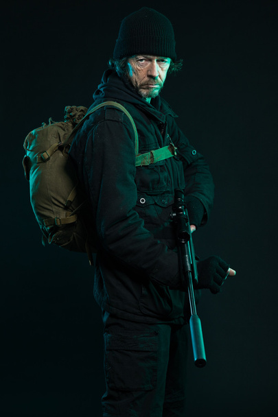 Sniper with beard in black holding gun. Studio shot. - Fotoğraf, Görsel