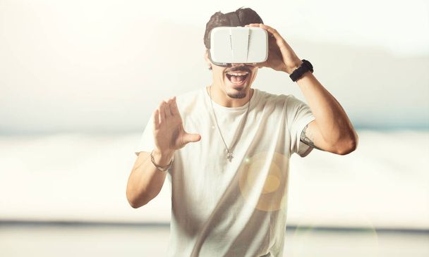 junger Rapper aufgeregt und unterhaltsam, spielt mit Virtual-Reality-Brille, erkundet eine Fantasiewelt, versucht etwas zu berühren - Foto, Bild