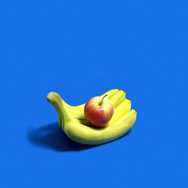 Pomme repose sur les bananes comme sur la paume ouverte de la main. Prends des fruits. Idée créative, imagination et fantaisie. Minimalisme. Couleurs vives à la mode. Concept alimentaire original
 - Photo, image