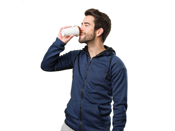 jongeman drinken van een kopje koffie op witte achtergrond geïsoleerd - Foto, afbeelding