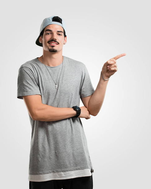 Young rapper man pointing to the side, smiling surprised presenting something, natural and casual - Foto, Imagem