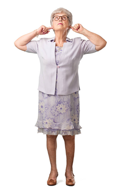 Full body senior woman covering ears with hands, angry and tired of hearing some sound - 写真・画像