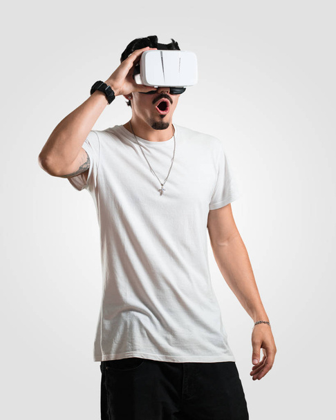 Jonge rapper man opgewonden en vermaakt, spelen met VR-bril, een fantasiewereld verkennen, proberen te raken iets - Foto, afbeelding