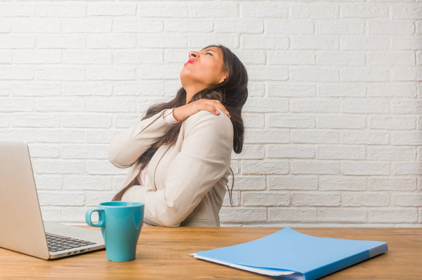Jeune femme indienne au bureau avec des maux de dos dus au stress au travail, fatiguée et astucieuse
 - Photo, image