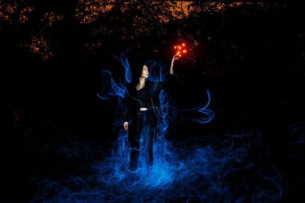 heks spelen met lichten als vuur in het bos tijdens halloween - Foto, afbeelding