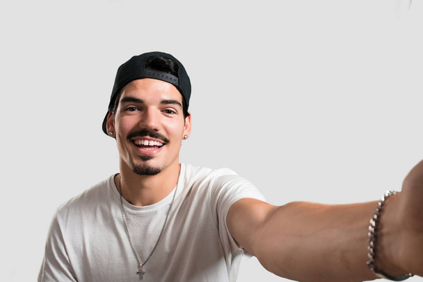 Fiatal rapper ember mosolyogva, és boldog, a selfie, tartja a kamerát, hogy izgatott a nyaralást, vagy a fontos esemény, vidám kifejezés - Fotó, kép