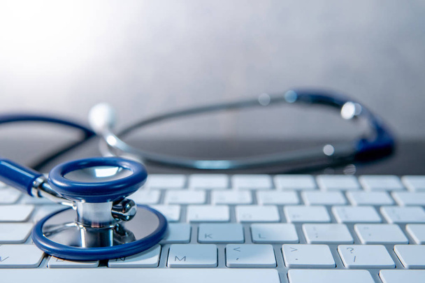 Orvostudomány technológia koncepció. Kék sztetoszkóp fehér modern billentyűzet orvos asztalon. Gyógy- és wellness háttér. Globális egészségügyi üzleti. Számítógép vírusvédelem - Fotó, kép