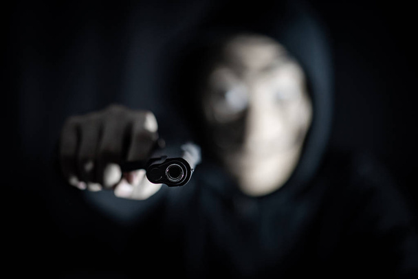 Uomo assassino con cappuccio e maschera misteriosa con pistola. Ladro o ladro anonimo che commette il crimine
. - Foto, immagini