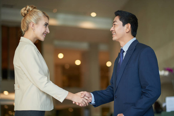 Cheerful multi-ethnic business people shaking hands at meeting - Photo, Image