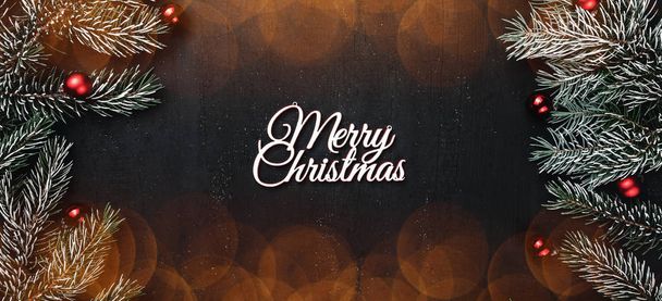Haut, haut, vue d'en haut, branches persistantes, globes d'arbres et inscription blanche Joyeux Noël sur fond noir, avec des ampoules
 - Photo, image