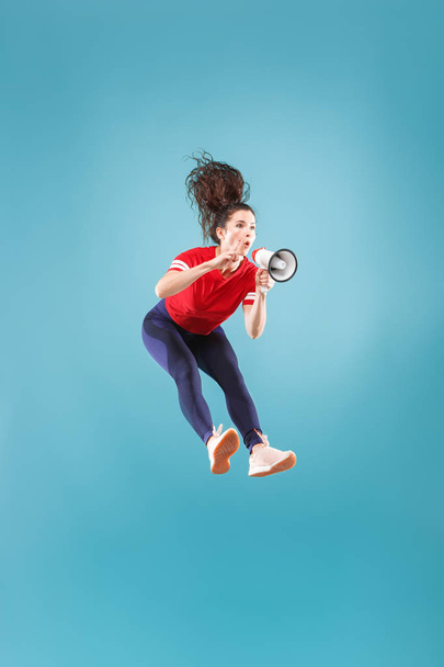 Beautiful young woman jumping with megaphone isolated over red background - Zdjęcie, obraz