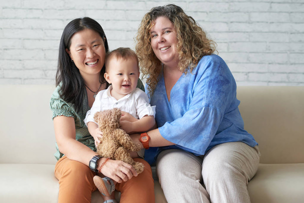 Multi-ethnic female lesbian couple with son at home on sofa  - Photo, Image