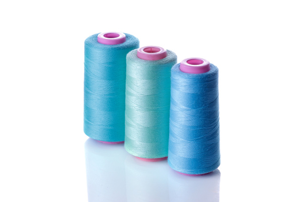 Una bobina con hilos en tonos azules sobre un fondo blanco aislado. accesorios para coser
 - Foto, imagen