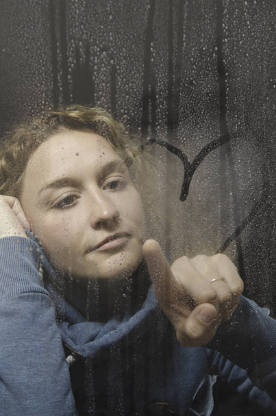 γυναίκα ματιά μέσα από το παράθυρο βροχερή - Φωτογραφία, εικόνα