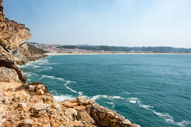 Nazare, Portekiz - 20 Eylül 2018: Altın taş kayalıklarla yeşil deniz ve arka plan Nazare, Portekiz Nazare Köyü - Fotoğraf, Görsel