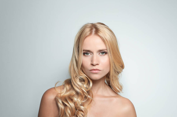 Krásná žena s zdravými dlouhými blonďatými vlasy na světlé pozadí - Fotografie, Obrázek