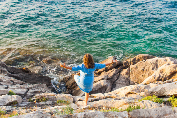 Girl having fun standing on the rocks near the sea - Zdjęcie, obraz