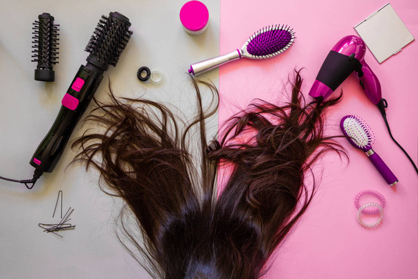 Narzędzia profesjonalne fryzjerskie i brunetka na różowym tle - Zdjęcie, obraz
