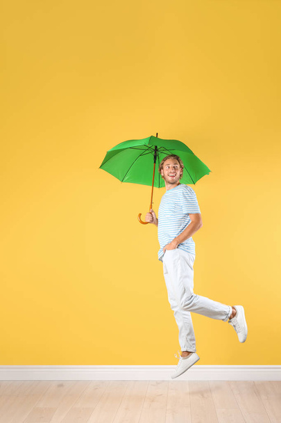 Man with green umbrella near color wall - Photo, Image