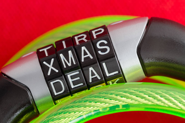 Lettera combinazione di lucchetto bici con il codice Xmas Deal per sbloccare il cavo di sicurezza in acciaio ricoperto di plastica verde su uno sfondo festivo festa rossa in un'immagine concettuale
 - Foto, immagini
