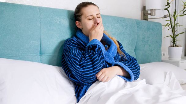 Portrait de jeune femme avec grippe relaxante au lit et toux
 - Photo, image