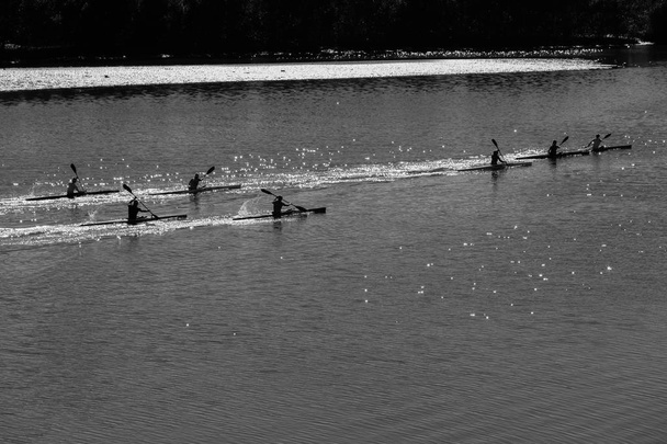 Спортсмены гребцы на каноэ утром тренируются в стеклянных речных водах с видом на пейзаж
 - Фото, изображение