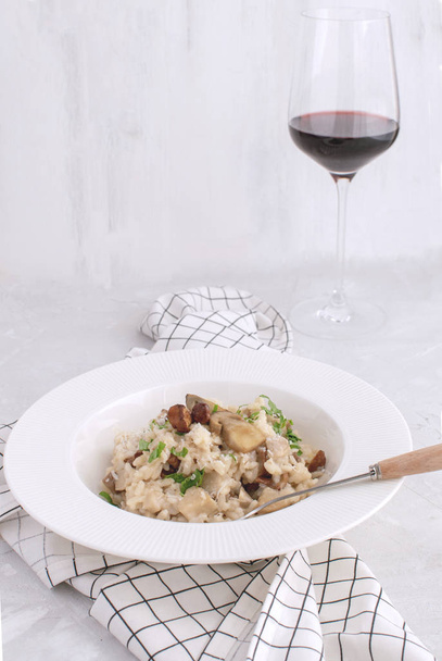 Risotto ai funghi Tradizionale riso porcino italiano bicchiere di vino rosso Piatto Fondo bianco Tovagliolo a quadretti Copia spazio
 - Foto, immagini