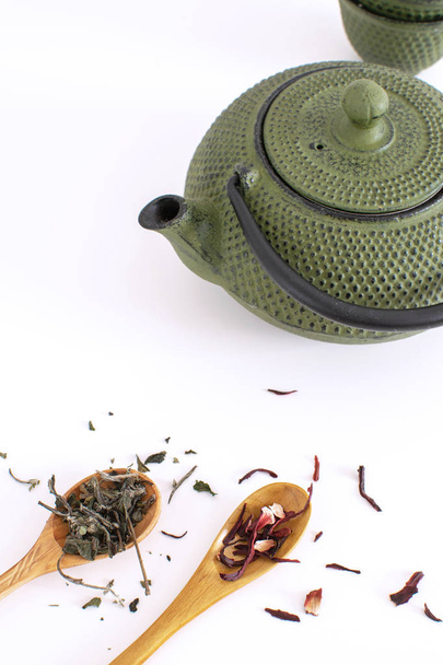 Cérémonie du thé Théière en fer Tasses Cuillère en bois Feuilles de thé hibiscus séché Fond blanc Espace de copie Pose plate
 - Photo, image