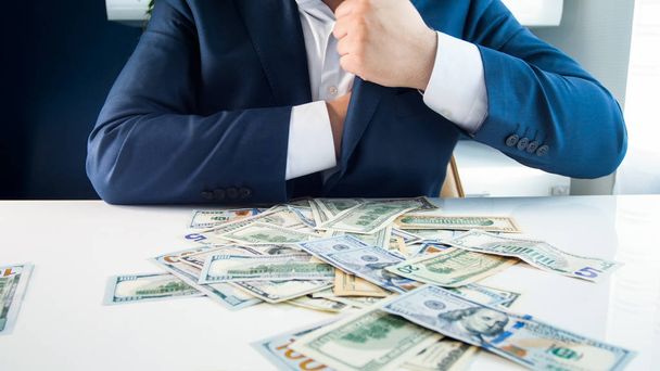Foto de primer plano del codicioso hombre de negocios llenando sus bolsillos con dinero
 - Foto, imagen