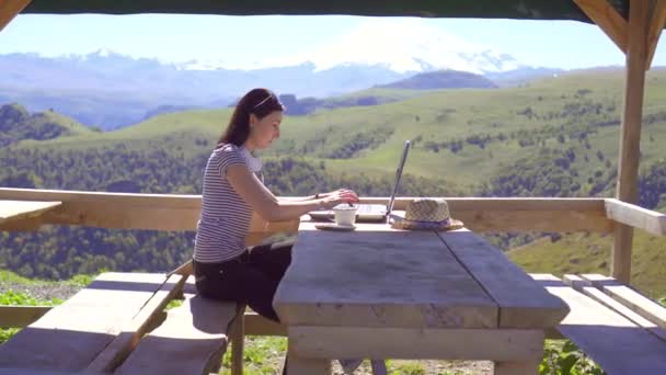 Freelancer-Mädchen arbeitet aus der Ferne am Laptop in den Bergen, Sonne - Filmmaterial, Video