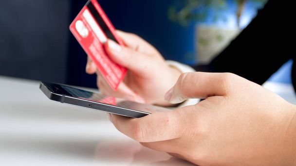 Closeup photo of young woman holding smartphone and credit card - Photo, Image