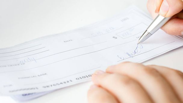 Closeup image of businesswoman signing personal bank cheque - Photo, Image
