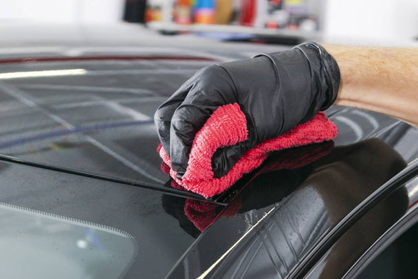 A man cleaning car with microfiber cloth, car detailing (or valeting) concept. Selective focus. Car detailing. Cleaning with sponge. Worker cleaning. Microfiber and cleaning solution to clean - Foto, imagen