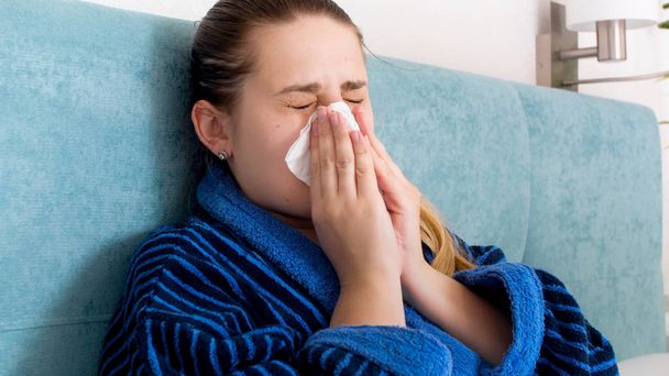 Closeup portrait of sick woman with allergy blowing runny nose in paper handkerchief - Photo, Image