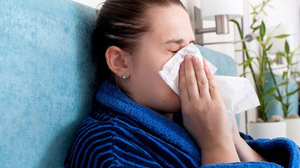Retrato de cerca de una mujer joven con alergia estornudando en papel
 - Foto, imagen