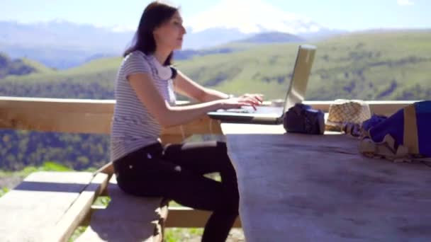 Dziewczyna freelancer z powodzenie radość laptop, z górami w tle - Materiał filmowy, wideo