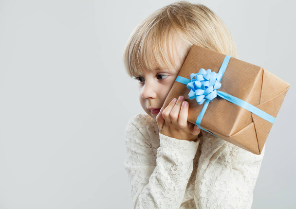Cute child girl with gift box on white background with copy space - Φωτογραφία, εικόνα