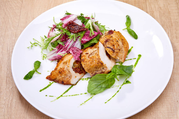 kipfilet met salade op witte plaat, close-up  - Foto, afbeelding