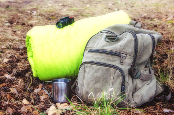 Things for hiking near the backpack and sleeping bag in the forest, closeup. - Foto, Imagem