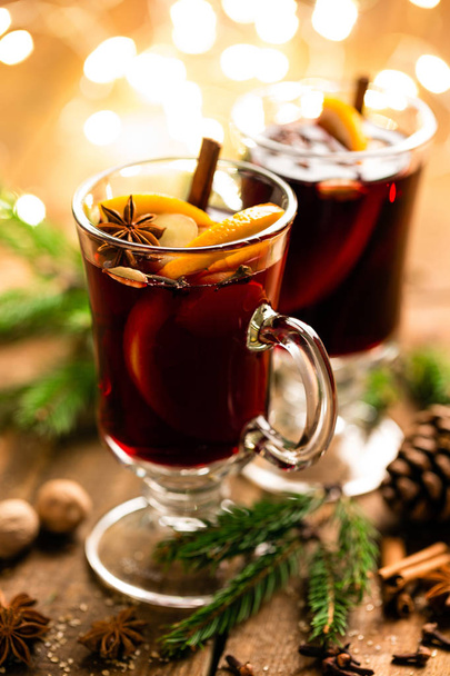 Christmas mulled red wine with spices and oranges on a wooden rustic table. Traditional hot drink at Christmas - Photo, image